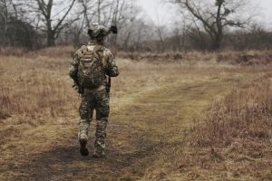 man in army suit walking along brown grass