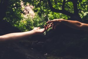 two hands sharing a joint outside