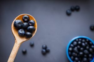 bowl and spoon of blueberries on purple backdrop