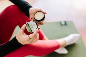 female in red leggings holding CBD balm